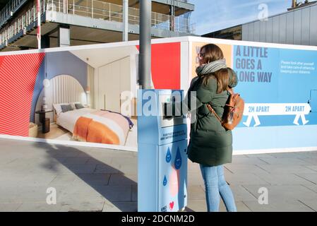 Brunette Frau Händewaschen in öffentlichen Händedesinfektionseinheit an Ort und Stelle für die aktuelle covid19 Pandemie. Kings Cross, London. Stockfoto