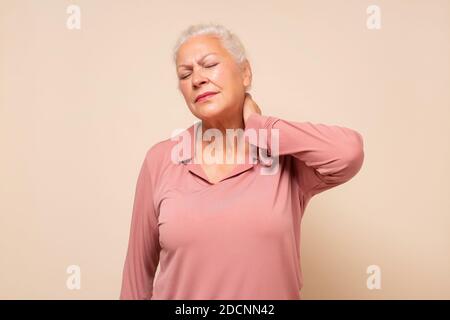 Ältere hispanische Frau, die ihren Hals in Schmerzen und Beschwerden hält. Studioaufnahme Stockfoto