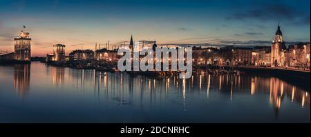 Panoramablick auf den alten Hafen von La Rochelle bei der blauen Stunde mit seinen berühmten alten Türmen Stockfoto