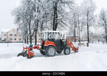 Straßen von Schnee freiräumen. Red Bagger reinigt die Spuren von Schnee in einem Blizzard. Schnee driftet auf den Straßen. Stockfoto