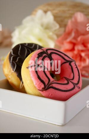 Zwei Donuts in weißer Schachtel. Rosa und Schokolade Donuts. Stockfoto