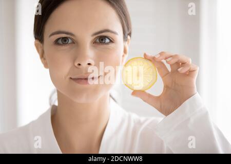 Hübsche Frau im Bademantel demonstriert Scheibe saftig frische Zitrone Stockfoto