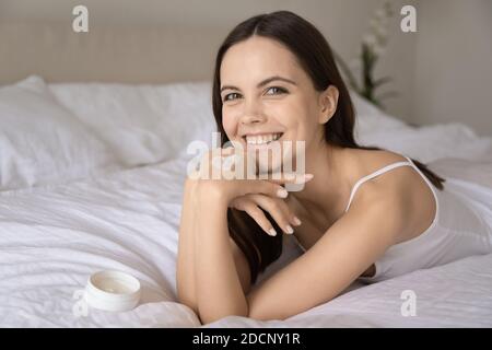Glücklich weiblich zeigt lustige Herz der feuchtigkeitsspendenden Creme auf der Hand Stockfoto