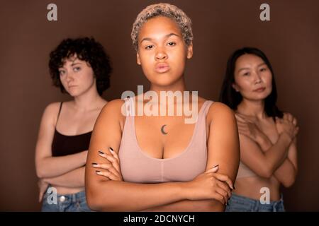 Junge seriöse blonde Mixed-Race-Frau vor zwei stehen Andere Frauen Stockfoto