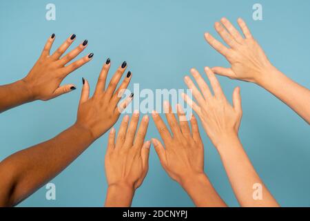 Drei Paar gestreckte Arme interkultureller junger Frauen in Vorderseite der Kamera Stockfoto