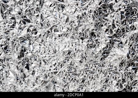 Silbernes, zerknittertes, glänzendes Metallpapier. Graue Tinfoil Textur für Urlaub. Aluminium gekräuselt Küche Folie Hintergrund. Abstraktes Muster aus Metall. Glänzend Stockfoto