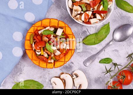 Vegan gebackenes rotes Kürbisgemüse mit Paprika, Tomaten und Pilzen, umgeben von Zutaten Stockfoto