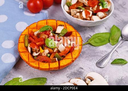 Vegan gebackenes rotes Kürbisgemüse mit Paprika, Tomaten und Pilzen, umgeben von Zutaten Stockfoto