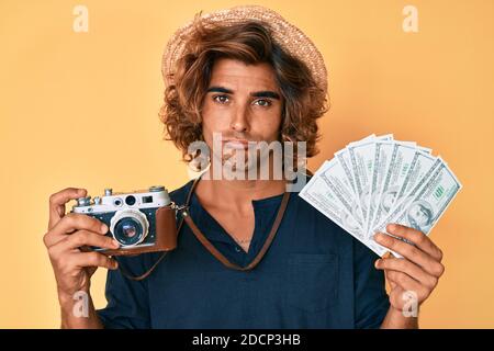 Junge hispanic Mann hält vintage Kamera und Dollar deprimiert und sorgen für Not, Weinen wütend und Angst. Trauriger Ausdruck. Stockfoto