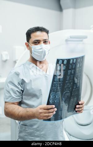 Professioneller Radiologe mit gemischter Rasse in Maske und einheitlicher Röntgenaufnahme Stockfoto