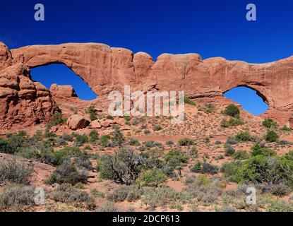 Blick Durch Den North Und South Window Arches National Park Utah An EINEM sonnigen Sommertag mit KLAREM blauen Himmel Und EIN paar Wolken Stockfoto