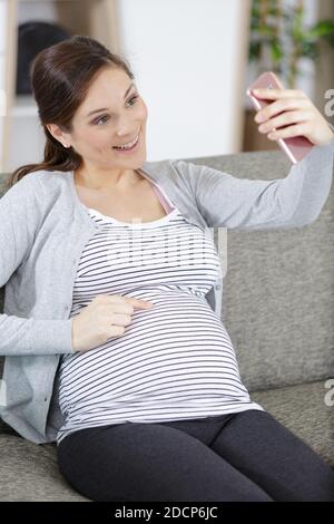 Schwangere junge Frau macht Selfie am Telefon Stockfoto