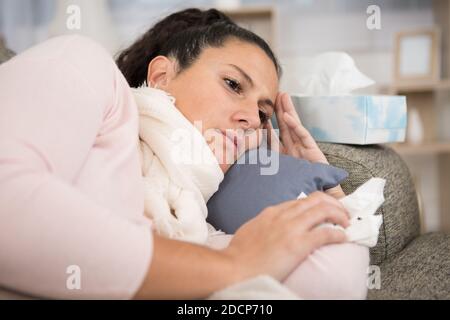 Junge Frau liegt schlecht auf sofe-Holding-Gewebe Stockfoto