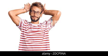 Schöner blonder Mann mit Bart tragen lässige Kleidung und Brille tun Bunny Ohren Geste mit Händen Handflächen zynisch und skeptisch. ostern Rabbi Stockfoto