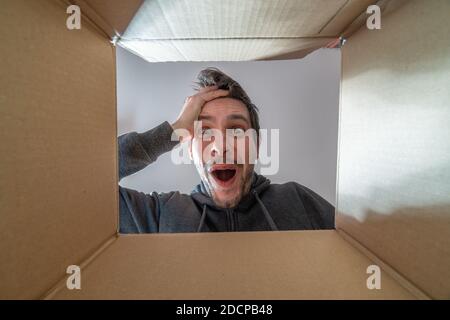 Glücklich und überrascht Mann öffnet ein Geschenk und Blick in Karton. Stockfoto