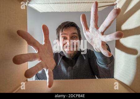 Glücklich und überrascht Mann öffnet ein Geschenk und Blick in Karton. Stockfoto