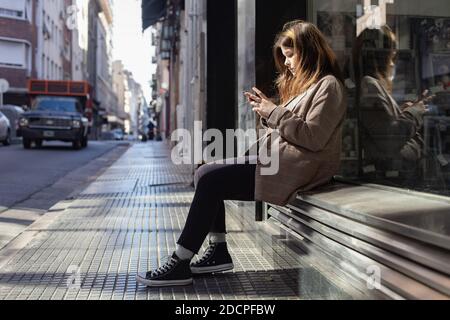 Teenager-Mädchen mit einem Smartphone auf einer Straße in Buenos Aires Stockfoto