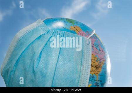 Eine Kugel in einer medizinischen Maske gegen einen blauen Himmel. Eine weltweite Pandemie, das Konzept des Schutzes gegen Coronavirus, Outdoor, Sommer Stockfoto