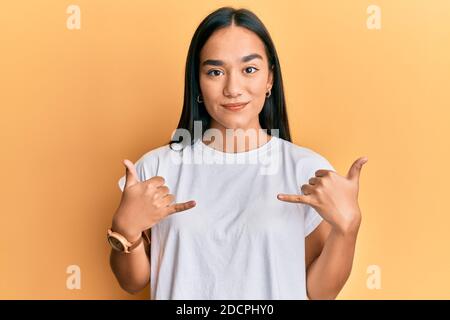 Junge asiatische Frau tun shaka Zeichen mit Händen entspannt mit ernsten Ausdruck auf Gesicht. Einfach und natürlich Blick auf die Kamera. Stockfoto