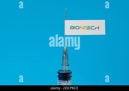 Stafford / Vereinigtes Königreich - November 22 2020: BioNTech-Impfstoff Covid-19 Konzept. Spritzennadel und Aufkleber darauf, verschwommener Hintergrund. Echtes Foto, nicht Stockfoto