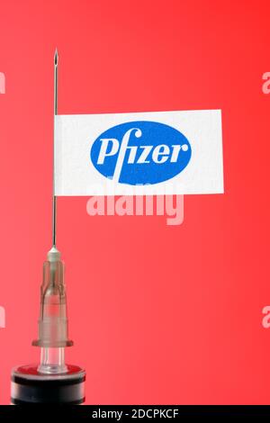 Stafford / Vereinigtes Königreich - November 22 2020: Pfizer-Impfstoff Covid-19 Konzept. Spritzennadel und Pfizer Aufkleber darauf, verschwommener Hintergrund. Echtes Foto Stockfoto