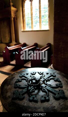 Schöne Bleiglasfenster Licht ins Kircheninnere mit Bänken und Taufbecken in St. Michael & All Angels Kirche in East Coker, England Stockfoto