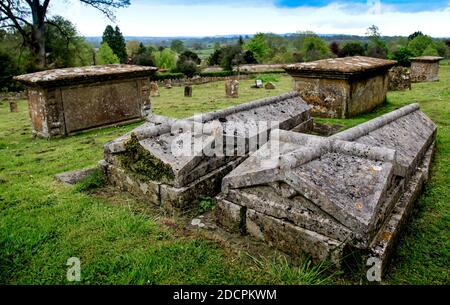 Ungewöhnlicher Stil von Twin Lawn Crypts in an Old Welt Pfarrfriedhof in St. Michael & All Angels Church Mit Blick auf eine hügelige Landschaft der englischen c Stockfoto