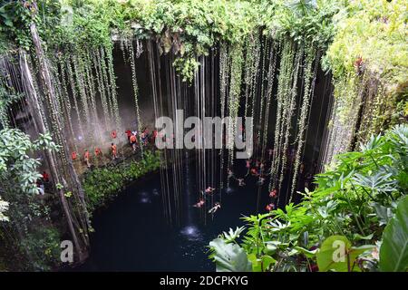 Blick hinunter in Cenote Ik Kil, Yucatan Peninsular, Mexiko. Besucher stehen am Rand des Cenote Schlange und warten darauf, in das tiefe Wasser zu springen. Stockfoto