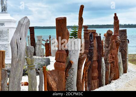 Eine Skulptur von Saint-Maurice wird von einem Zaun ​​of geschnitzten hölzernen Totems in der Bucht von St. Maurice, Vao, Insel Pines, Neukaledonien umgeben. Stockfoto