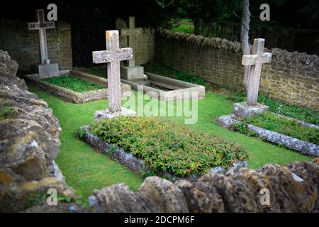 Gut gepflegter alter versunkener Friedhof mit steinernen Kreuzen, die mit Mauern umgeben sind Trockenstein und Sharpe-Kapselsteine im historischen Stil in St. Michael & All Angels Kirche in Stockfoto