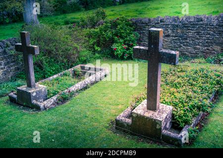 Gut gepflegter alter versunkener Friedhof mit steinernen Kreuzen, die mit Mauern umgeben sind Trockener Stein und scharfe Kapselsteine im historischen Stil in St. Michael & All Angels Kirche in Stockfoto