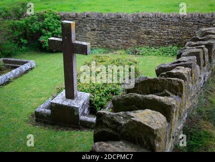 Gut gepflegter alter versunkener Friedhof mit steinernen Kreuzen, die mit Mauern umgeben sind Trockener Stein und scharfe Kapselsteine im historischen Stil in St. Michael & All Angels Kirche in Stockfoto