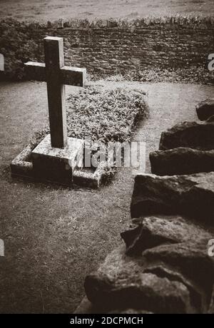 Gut gepflegter alter versunkener Friedhof mit Steinkreuzen, die mit trockenem Stein und scharfen Kopfsteinen in der St. Michael & All Angels Church, East Coker, England, UK, gemauert sind Stockfoto