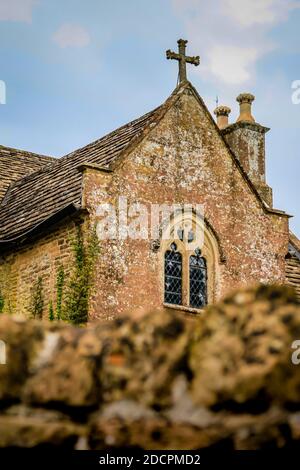 Ein Blick über die weiche Trockensteinmauer, an der historischen, Grade II* gelisteten St. Michael & All Angeles Kirche in East Coker, County Somerset, Englan Stockfoto