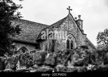 Ein Blick über die weiche Trockensteinmauer, an der historischen, Grade II* gelisteten St. Michael & All Angeles Kirche in East Coker, County Somerset, England Stockfoto