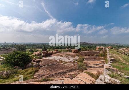 Hampi, Karnataka, Indien - 4. November 2013: Sunset Hill aka Hemakatu. Walls Ruinen und Felsbrocken unter blauer Wolkenlandschaft. Stockfoto