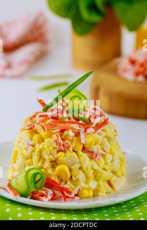 Salat aus Krabbenfleisch, Eiern und Mais auf einem weißen Teller. Meeresfrüchte-Gericht. Stockfoto