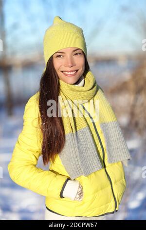 Happy cute asiatische Winter Frau im Schnee tragen gelbe Mode Oberbekleidung Outfit mit Strickwolle Accessoires Hut, Schal und Daunenjacke. Chinesisches Mädchen Stockfoto