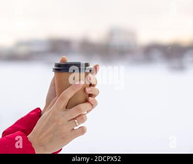 Eine junge Frau hält im Winter ein Glas heiß Kaffee oder Tee Stockfoto