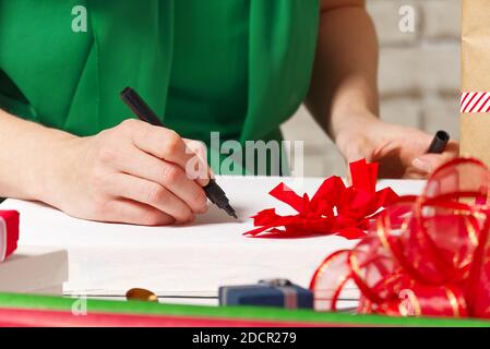 Frau unterzeichnet weihnachtsgeschenke mit einem schwarzen Stift. weihnachtsgeschenke Verpackung Stockfoto