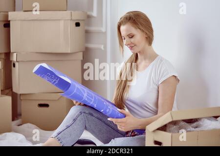 Das Mädchen, das zwischen den Kisten sitzt, markiert den Plan der Wohnung. Stockfoto