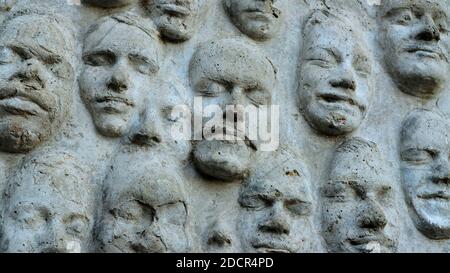 In Zement gegossene Gesichter auf einer verwitterten Wand am City College von San Francisco, Kalifornien; eine Vielzahl von Gesichtern mit geschlossenen Augen. Stockfoto