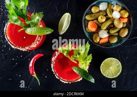 Bloody Mary Cocktails, darüber liegende flache Lay Shot mit Limetten und Gurken, die Getränke sind mit Limette und Sellerie garniert Stockfoto