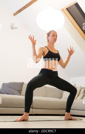 Schöne blonde Frau tun zu Hause Training drinnen. Frau praktiziert Yoga zu Hause. Fit Mädchen mit Workout-Tutorials für einen gesunden aktiven Lebensstil. Frau Stockfoto