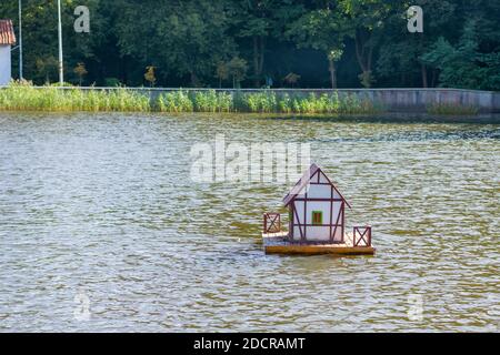 Holzhaus für Ente auf Wasser. Künstliches Gehäuse für Wildvögel auf dem Stadtersee. Selektiver Fokus. Stockfoto