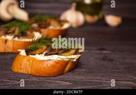 Bruschetta mit Pilzen. Sandwiches mit Weichkäse, Pilzen und Dill. Seitenansicht, Nahaufnahme. Gesundes leckeres Frühstück, italienische Küche. Stockfoto