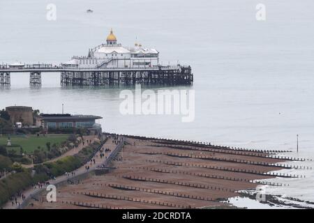 Menschen, die an einem kalten Wintertag entlang der Strandpromenade in der Nähe von Eastbourne Pier und Strand spazieren. Quelle: James Boardman Stockfoto