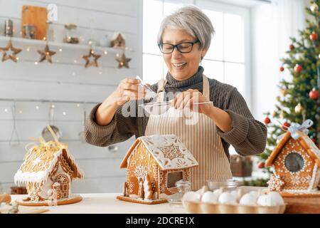 Frohe Weihnachten und frohe Feiertage. Familienzubereitung Urlaub Essen. Frau Kochen Lebkuchenhaus. Stockfoto