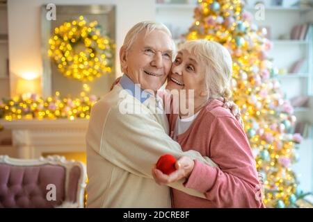 Grauhaariger Mann macht einen Vorschlag und eine glückliche Frau umarmt Er Stockfoto