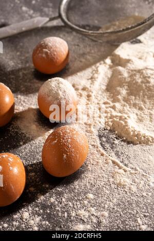 Selektiver Fokus. Zutaten für das Backen in hartem Licht. Eier und Mehl. Vertikale Position Stockfoto